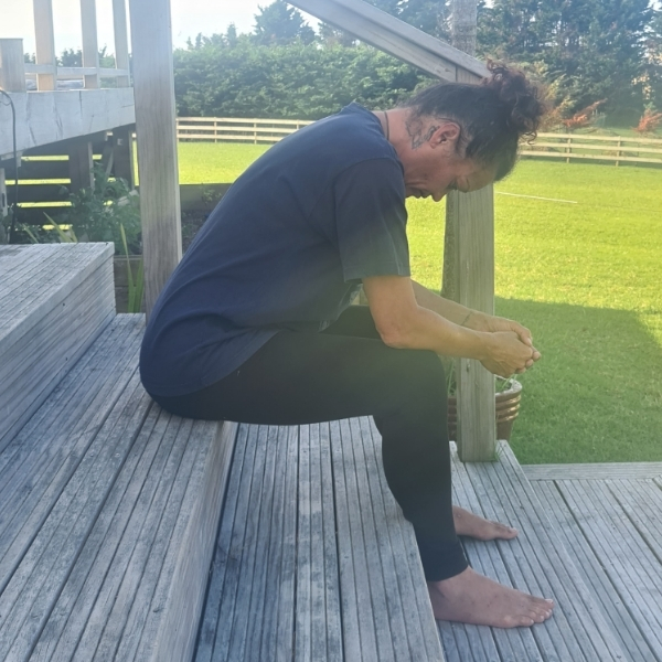 Woman sitting on step leaning forward with no support