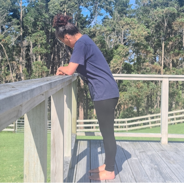 Woman standing, leaning forward against rail