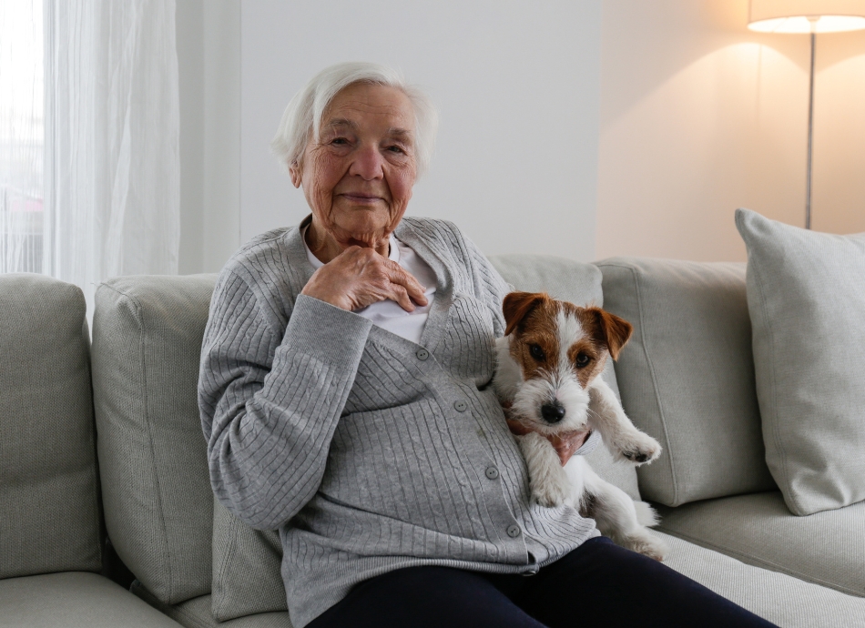 Older woman sitting on couch with dog 
