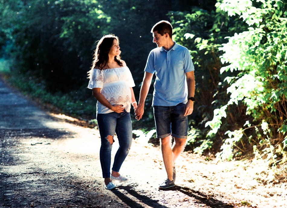 Pregnant couple walking in dappled light 