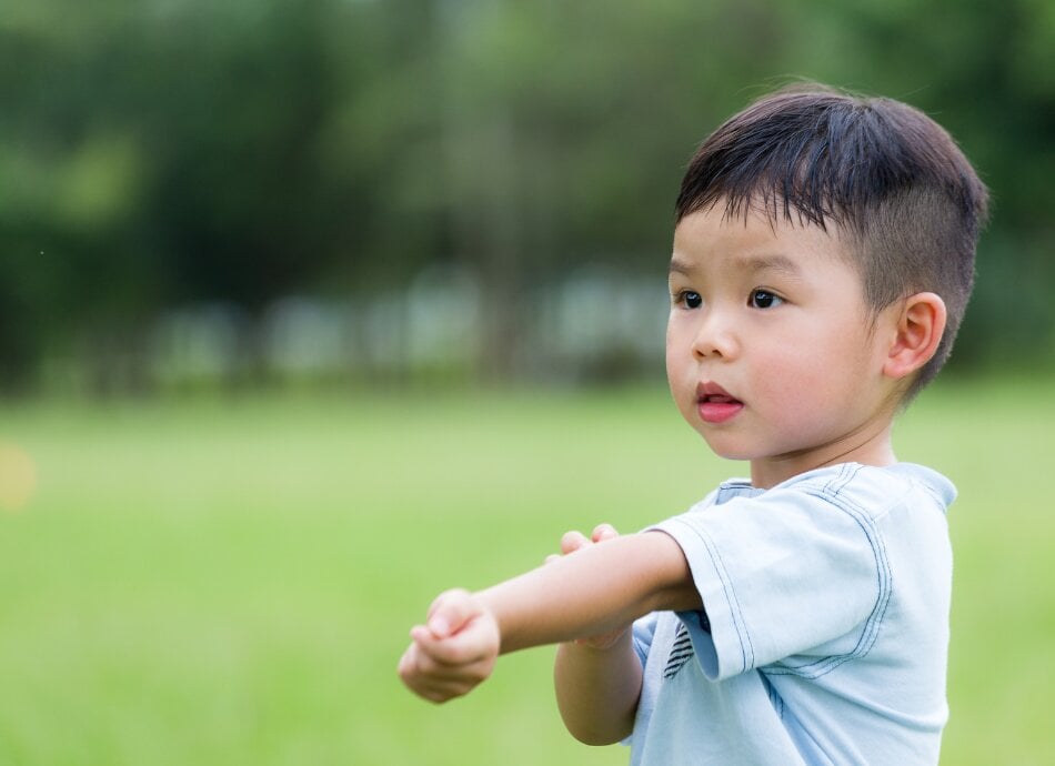 Small boy outdoors with itchy arm