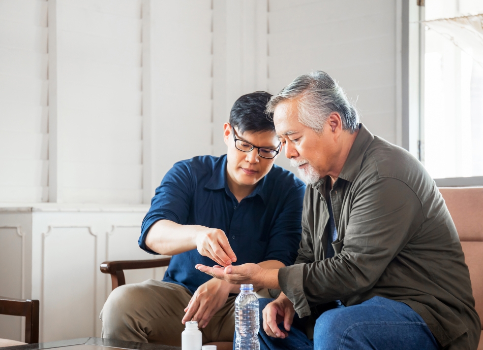 Son helping father take medicine with water 