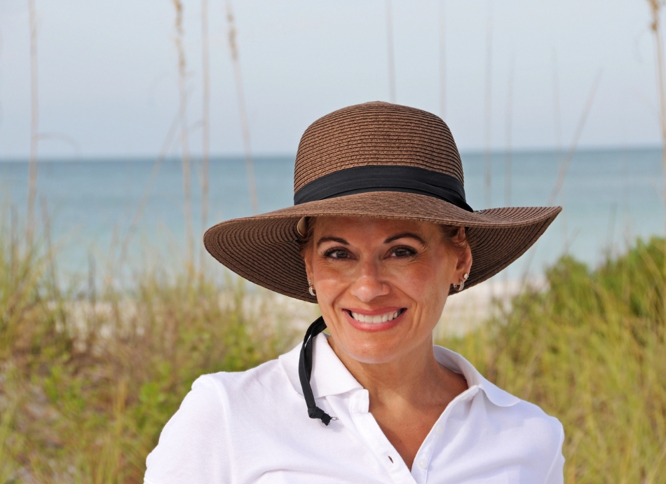 Woman at beach wearing long sleeves and sunhat 