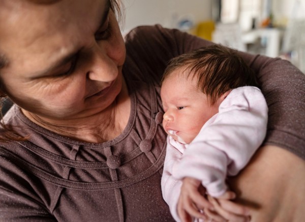 Woman holding baby with reflux, bringing up milk