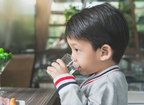 Young boys drinks a glass of water