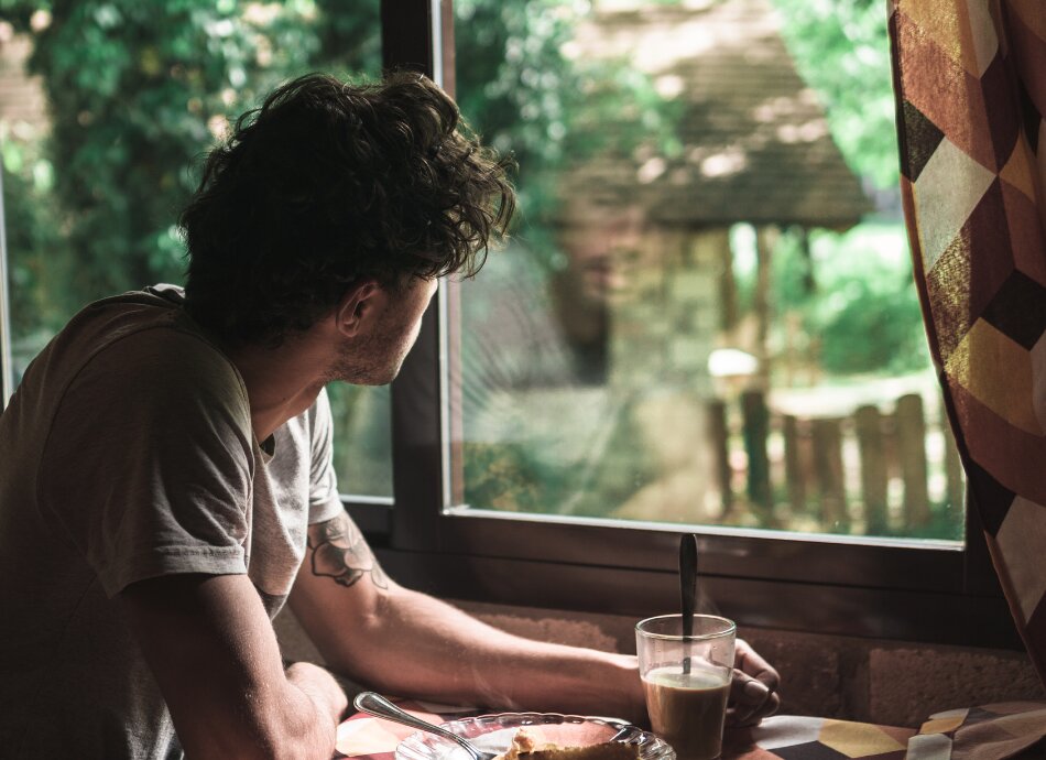 Young man looking out through window