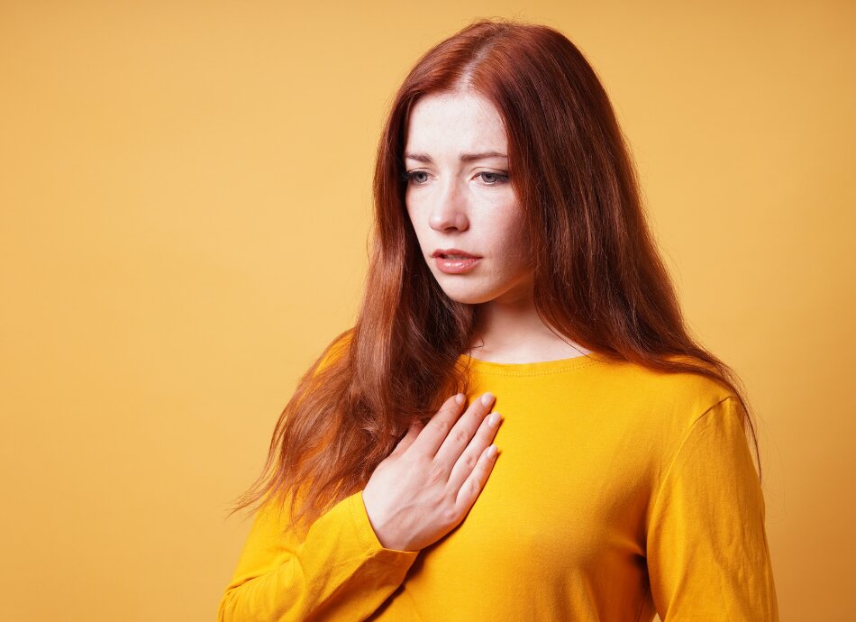 Young woman with hand on heart feeling anxious or panicked